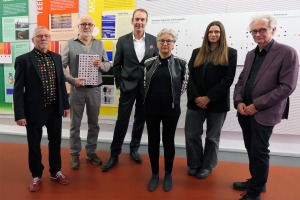 Eine Gruppe von Männern und Frauen steht vor Informationstafeln zum Thema