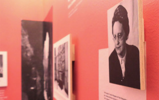 Blick in eine Ausstellung mit Text- und Fototafeln, die in schwarz/weiß dargestellt werden.