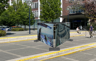 Bauzäune im öffentlichen Raum, dahinter sind Pflanzen, Gebäude und Menschen. - Bildcredit: Simulation public preposition: Baukunstarchiv NRW © Studio Mischa Kuball