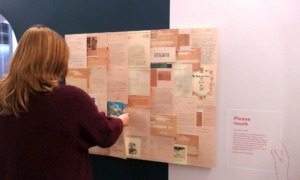 Eine Tafel mit vielen Dokumenten, davor steht eine Person, die sich die Dokumente an der Tafel anschaut.