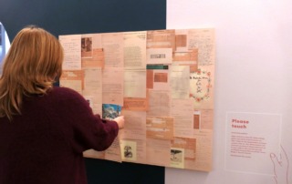 Eine Tafel mit vielen Dokumenten, davor steht eine Person, die sich die Dokumente an der Tafel anschaut.