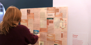 Eine Tafel mit vielen Dokumenten, davor steht eine Person, die sich die Dokumente an der Tafel anschaut.