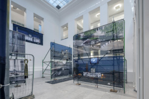 Bauzäune mit Bannern und Plakaten stehen in einem hellen Raum.